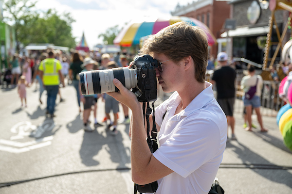 Photography intern holding a camera at an outdoor event