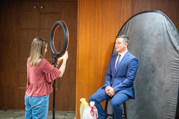 Intern taking a headshot of a student in professional clothes