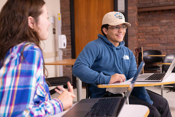 Two students talking in a classroom.