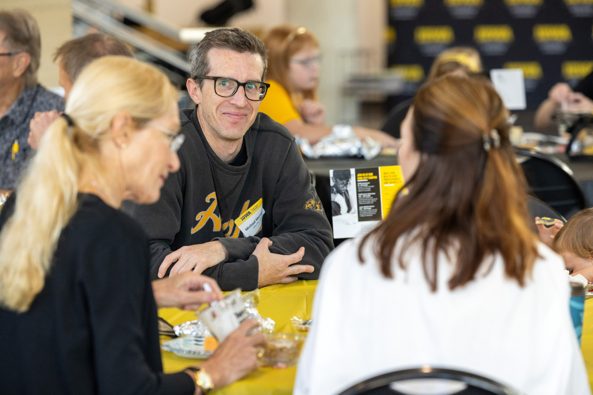 A man facing the camera listens to a woman speak across the table from him