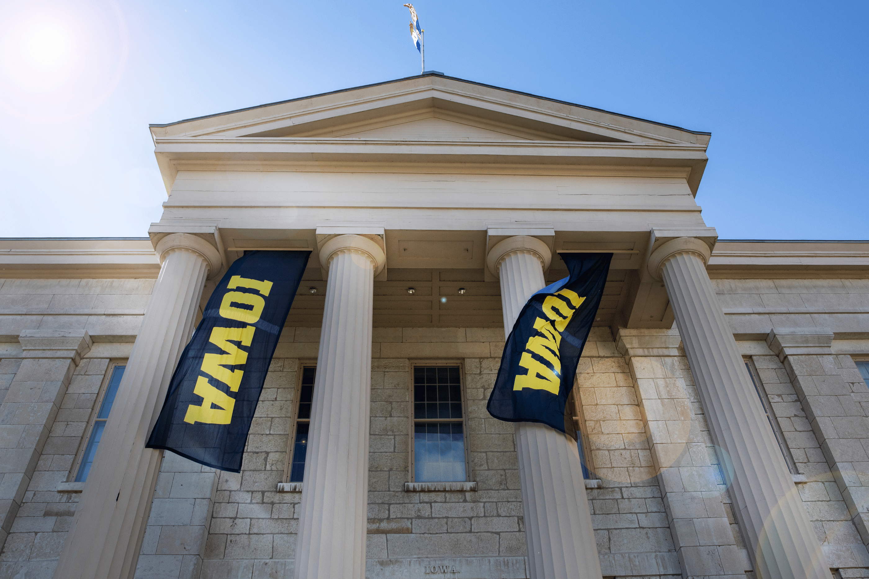 Schaeffer Hall with Iowa banners flanking the pillars and waving in the wind.