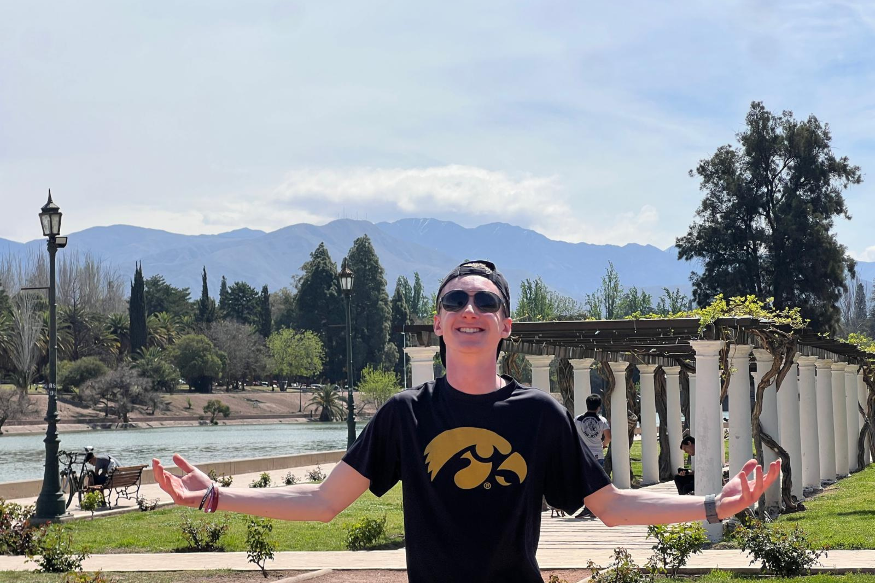 A student stands with arms wide with a mountain in the background