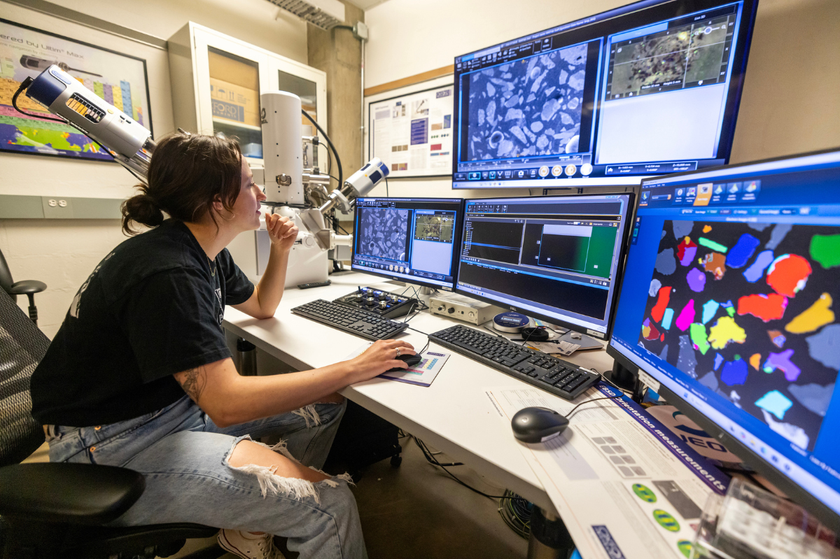 Woman sitting in front of a panel of four screens reviewing data