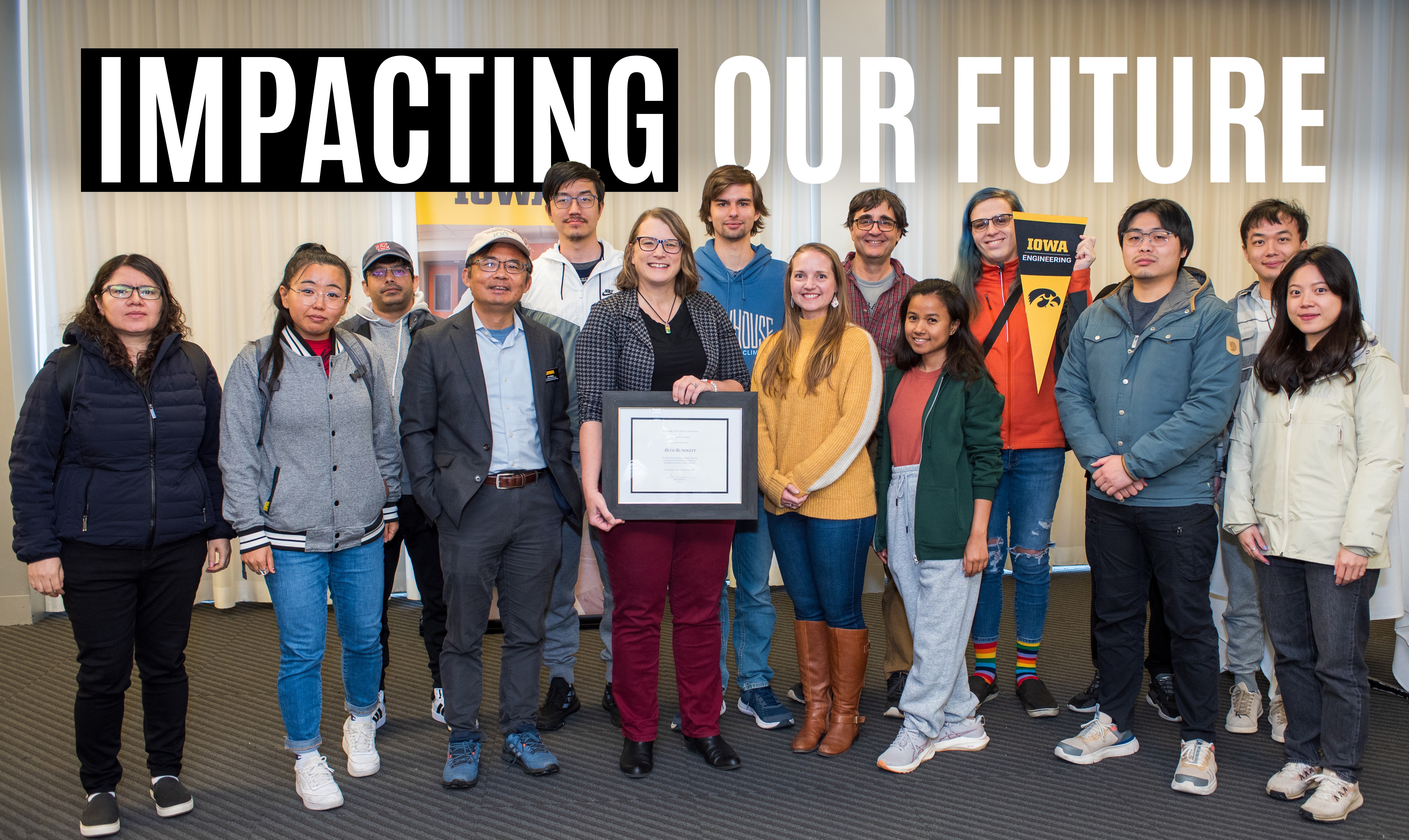 Beth Rundlett holds a plaque surrounded by colleagues from the Department of Chemical and Biochemical Engineering