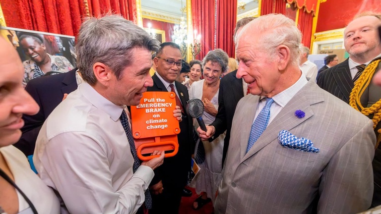King Charles III listens as Marcelo Mena presents a call to action on climate change during a reception at St. James’s Palace, with attendees gathered at St. James's Palace in London.