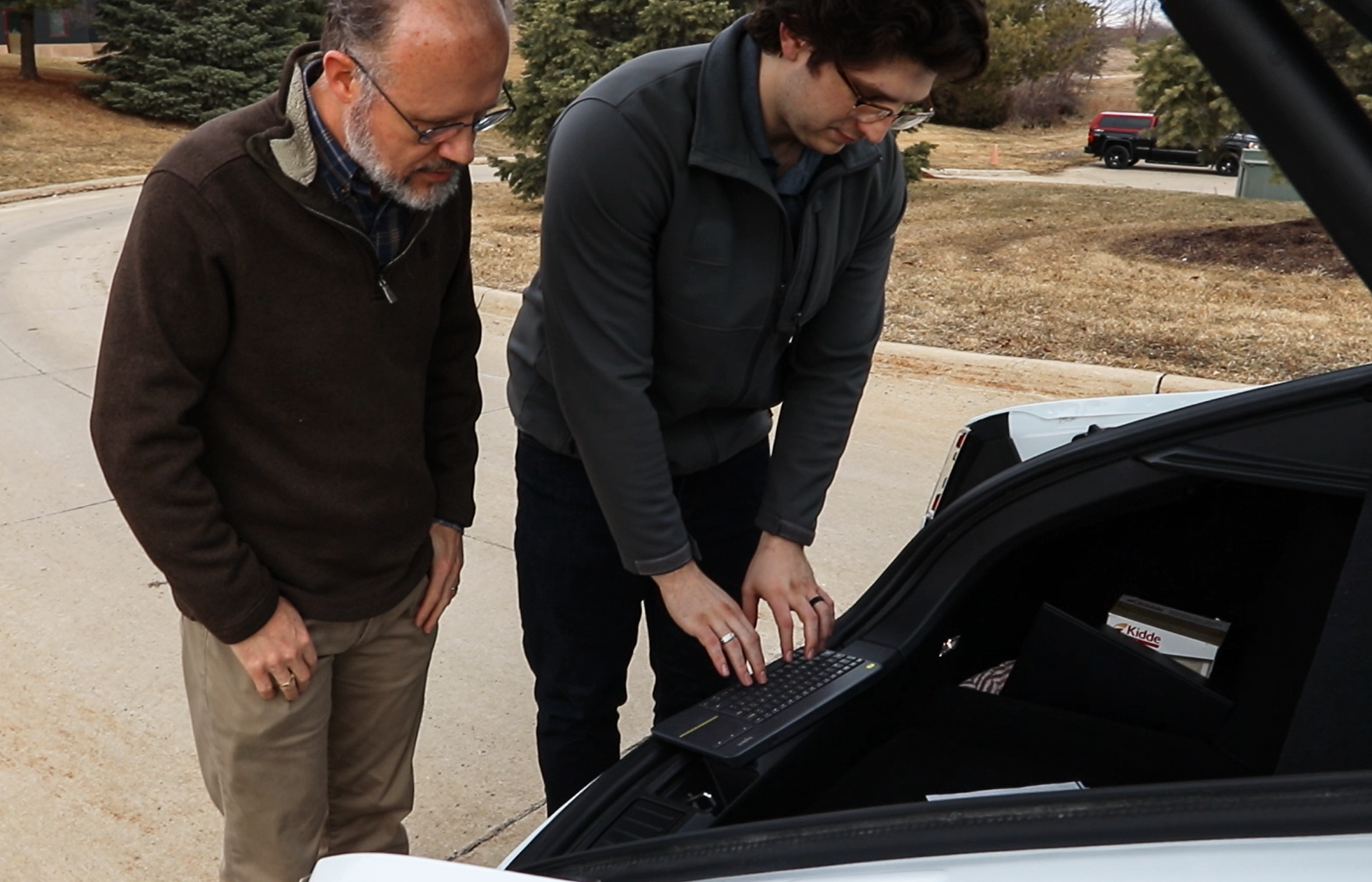 Schwarz and Rundus work on back of a Tesla electric vehicle