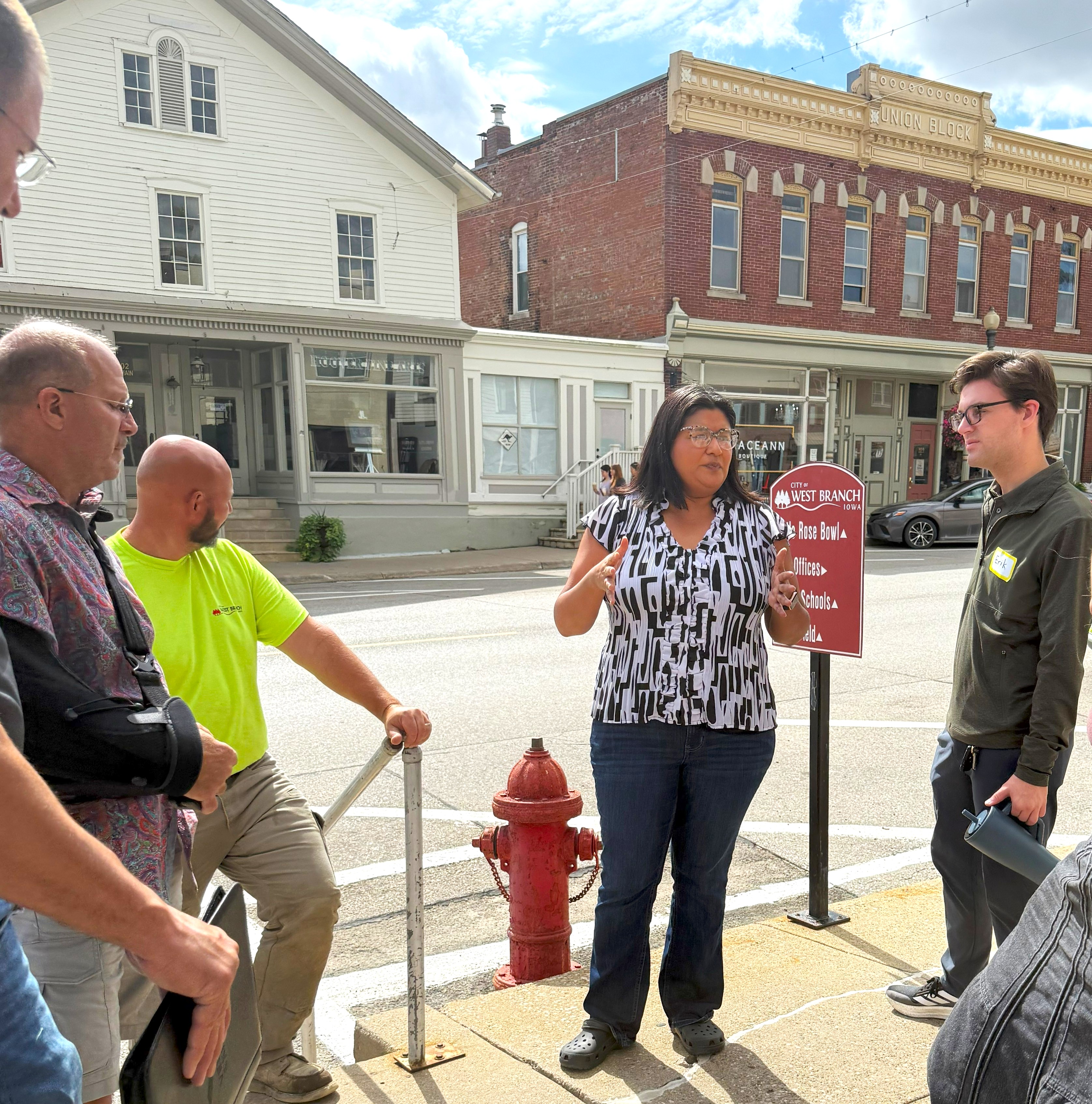 A group of people talking on a street corner in front of a historic brick building.