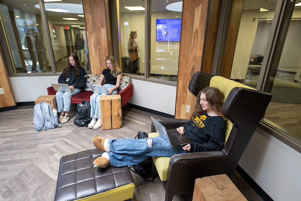 Three female students sit in the lounge in Stanley Hall studying on their laptops
