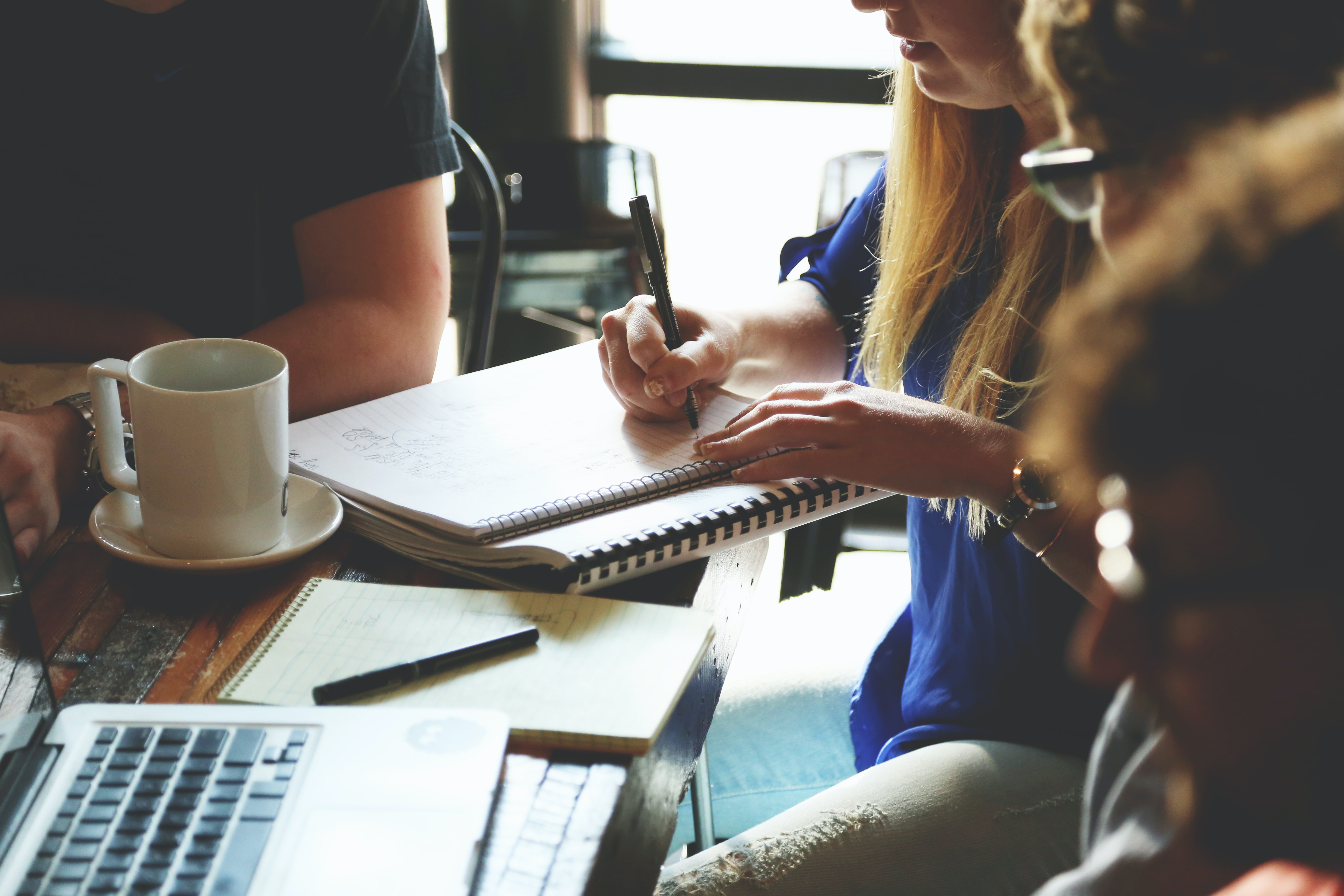 People sitting together at a table in a coffee shop, working on a project