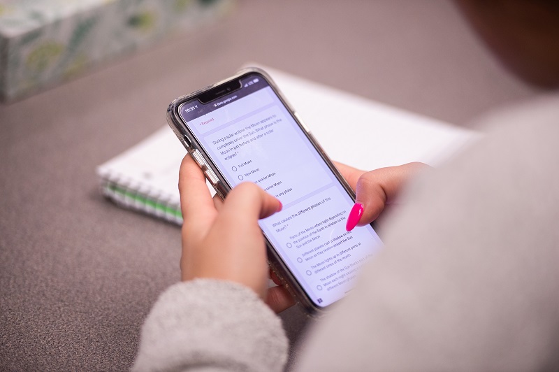 Closeup of an Iowa student using their cell phone to access Pressbooks for their textbook. 