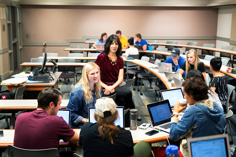 Iowa students chatting with their instructor in a classroom.