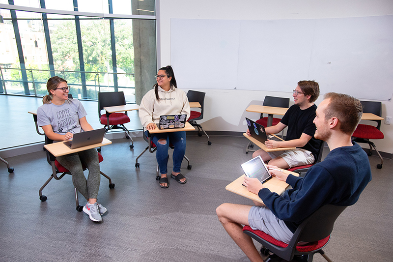 UI students engaging in conversation in a classroom.