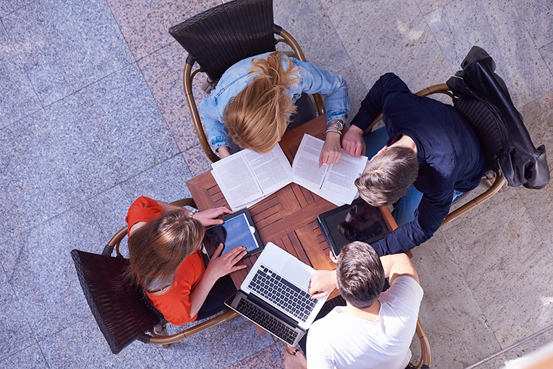 Aerial view of four students working at a table together.