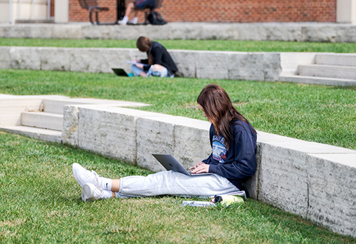 Ui students studying on the Pentacrest lawn.