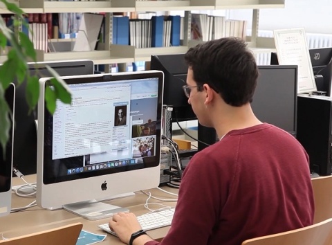 A student sits at a computers, checking their progress with Elements of Success.