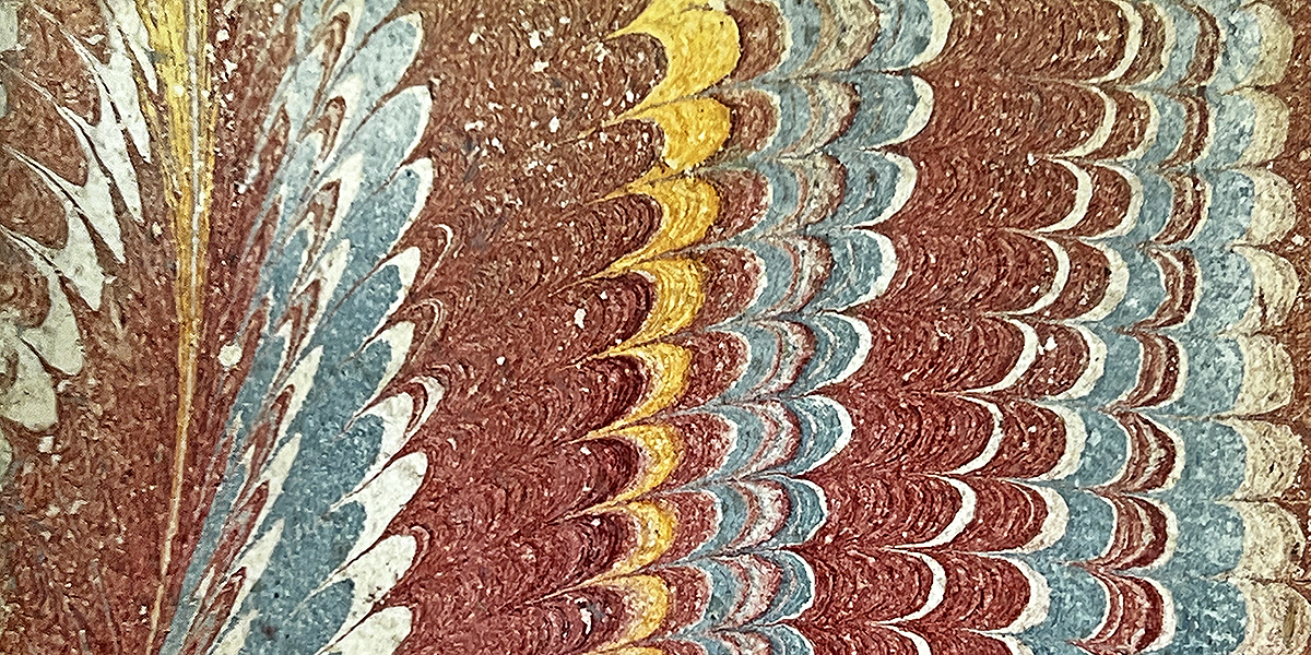 Color photo of the red, yellow, white, and blue marbled endpaper from a Sammelband of Louis's Dissertation sur la question--comment se fait la transmission des maladies héréditaires? [Dissertation on the question--how are hereditary diseases transmitted?] and Observation et remarques sur les effets du virus cancéreux [Observation and remarks on the effects of the cancer virus], 1749.