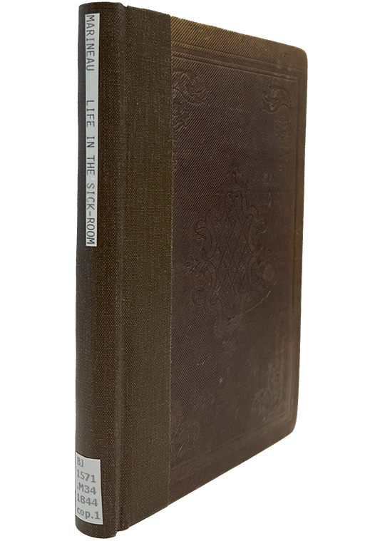 Color photo of the burgandy 19th century cloth cover with a brown cloth rebacked spine that includes the titel and call number printed black on white paper and glued to the cloth, from Martineau's Life in the sick room, 1844.