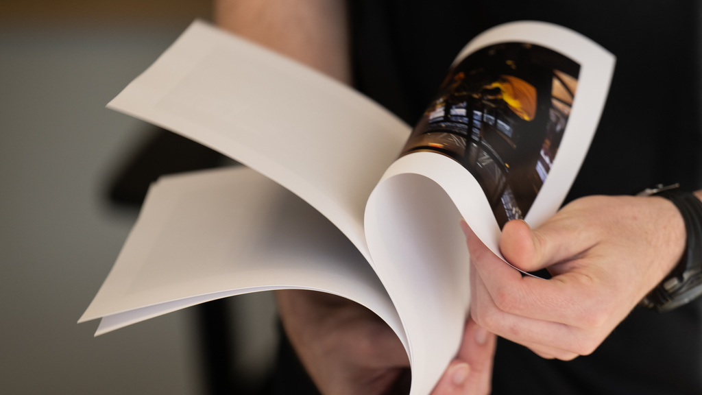 A person flipping through printed pages with a photograph on them