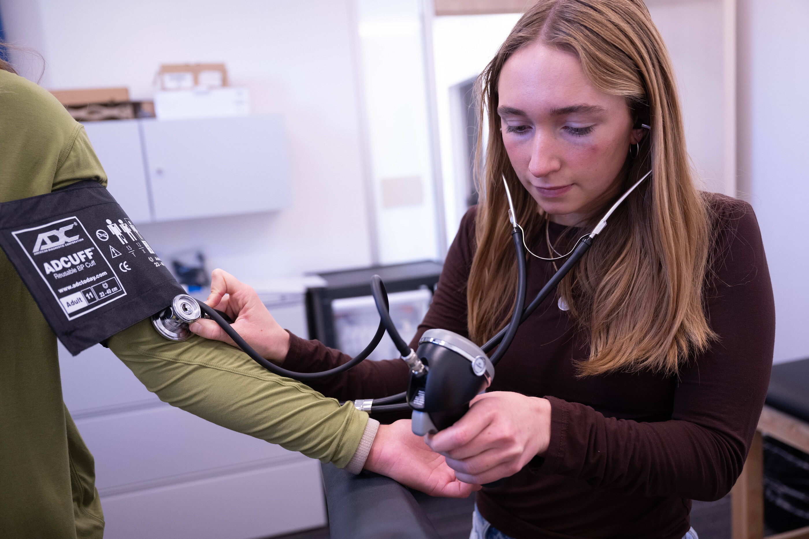 women takes blood pressure of human subject