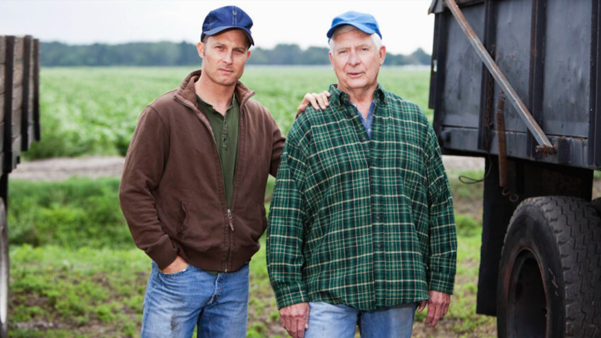 Farmer with father by trucks