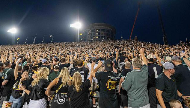 People participating in the Hawkeye Wave during a football game