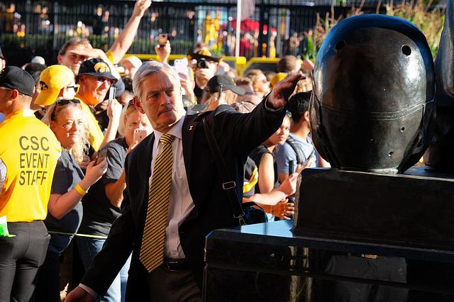 Kirk Ferentz touching the Nile Kinnick statue