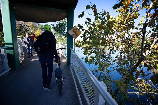 Person wheeling a bike on a bridge