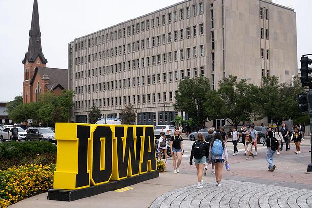 "Iowa" sign on the Pentacrest with Phillips Hall in the background 