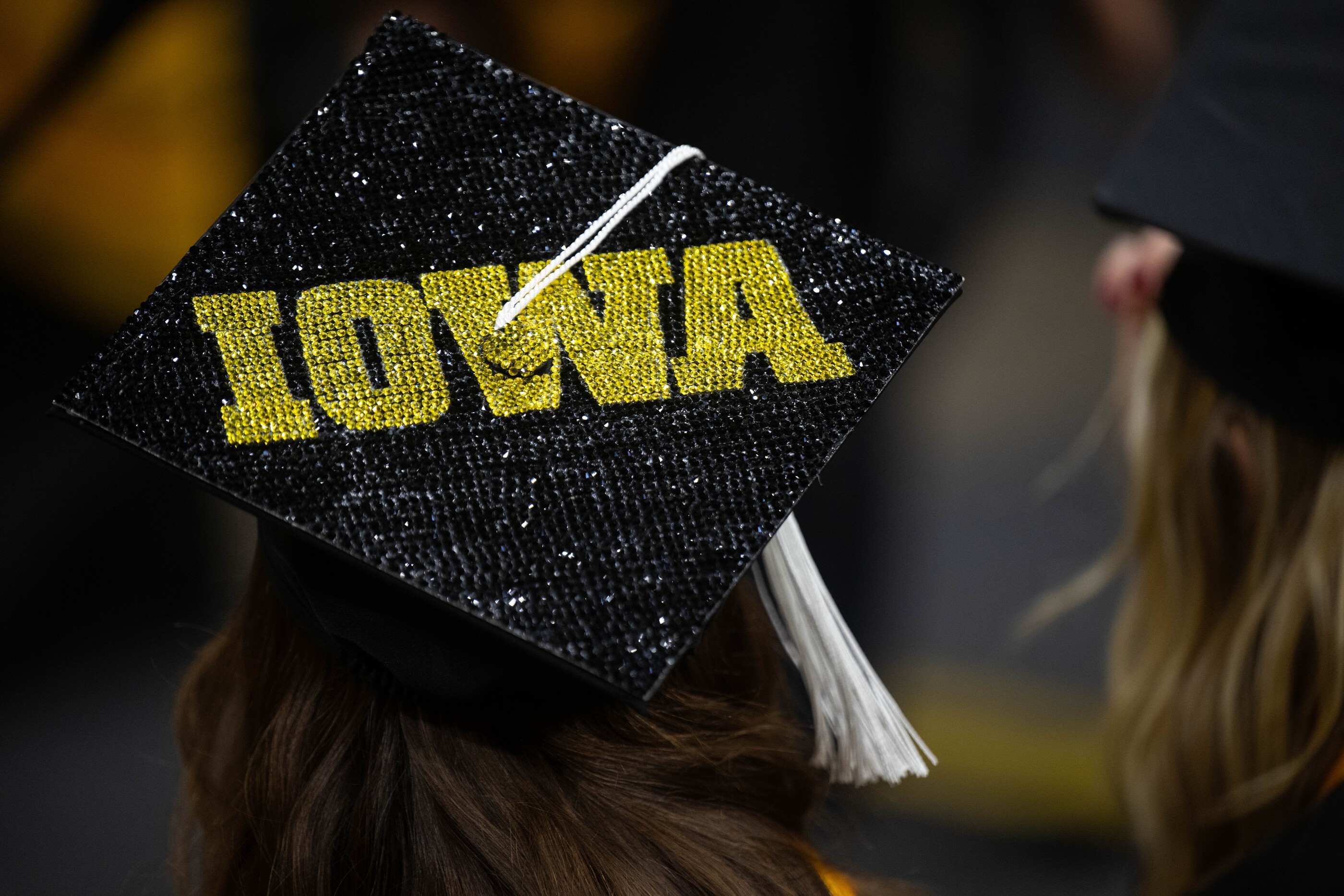 A graduation cap on a person's head that has IOWA spelled out in sequins