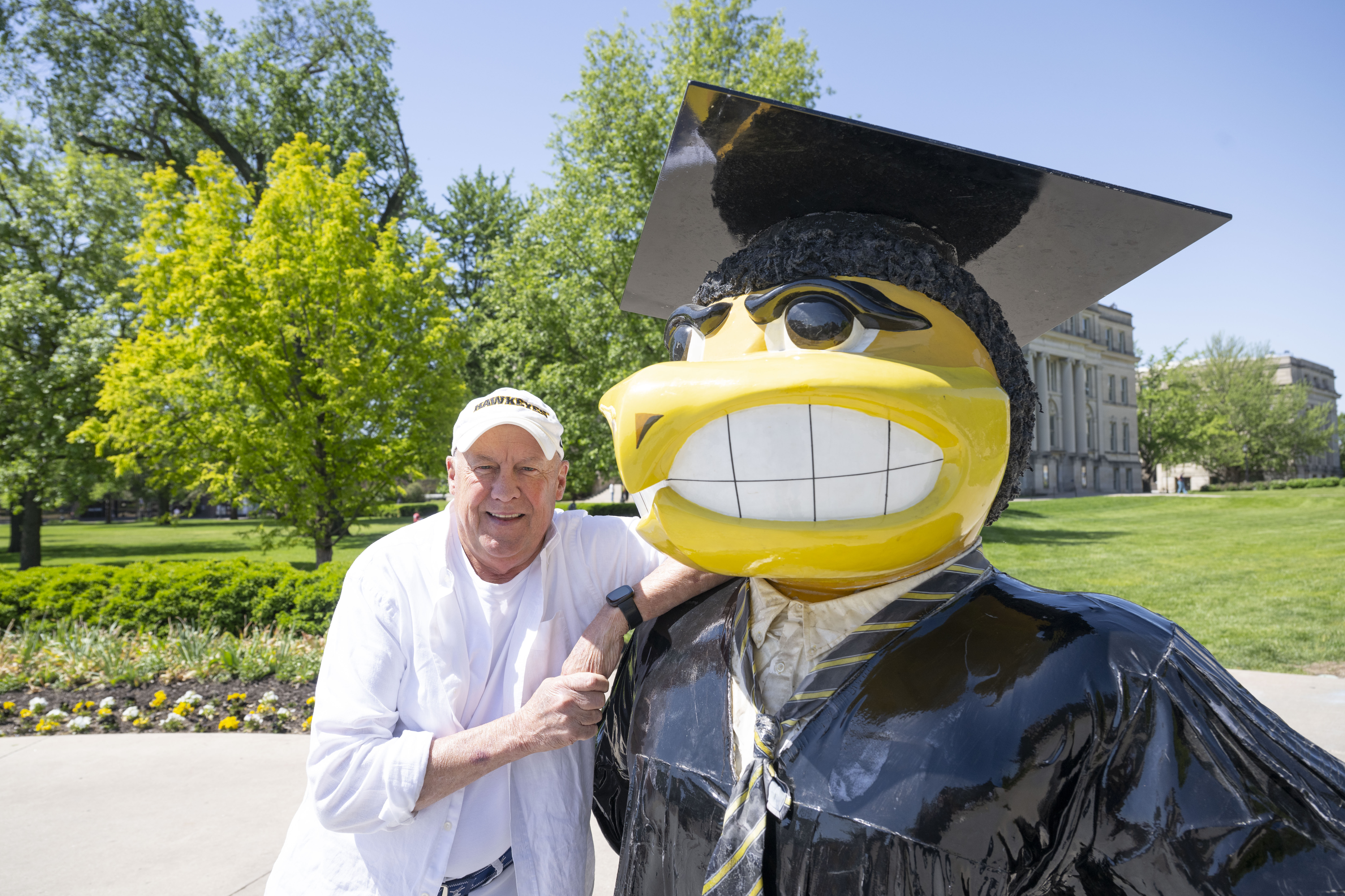 Tim Dickson poses on the Pentacrest with Graduation Herky