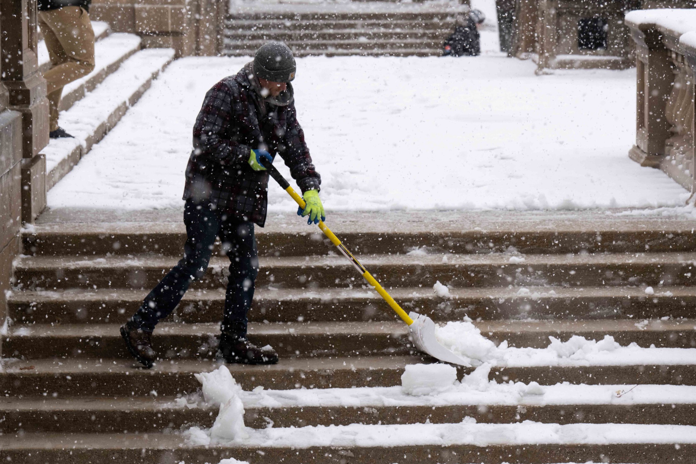 A person shoveling snow on stairs