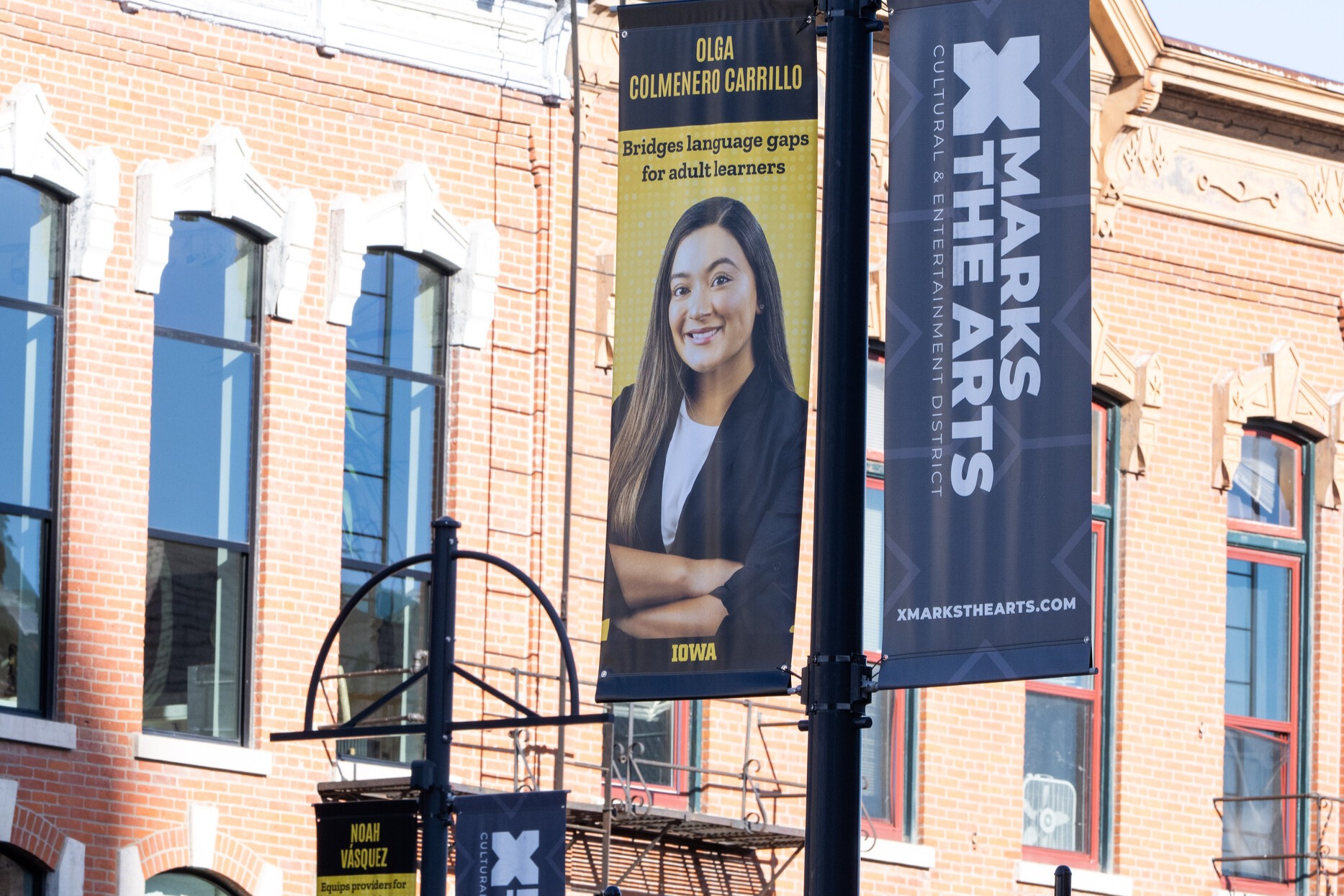 A banner on a light post in downtown Iowa City that is decorated with a photo of a Dare to Discover student