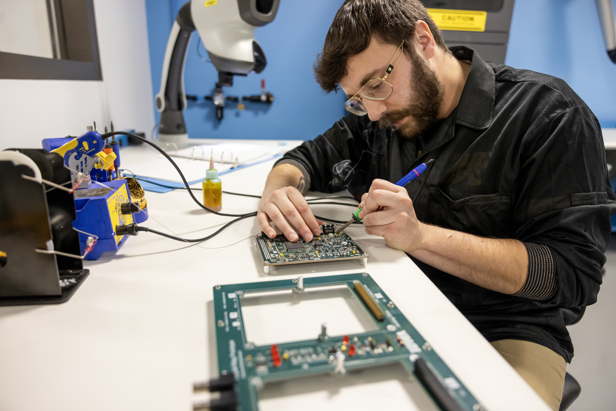 A person soldering parts on a computer motherboard.