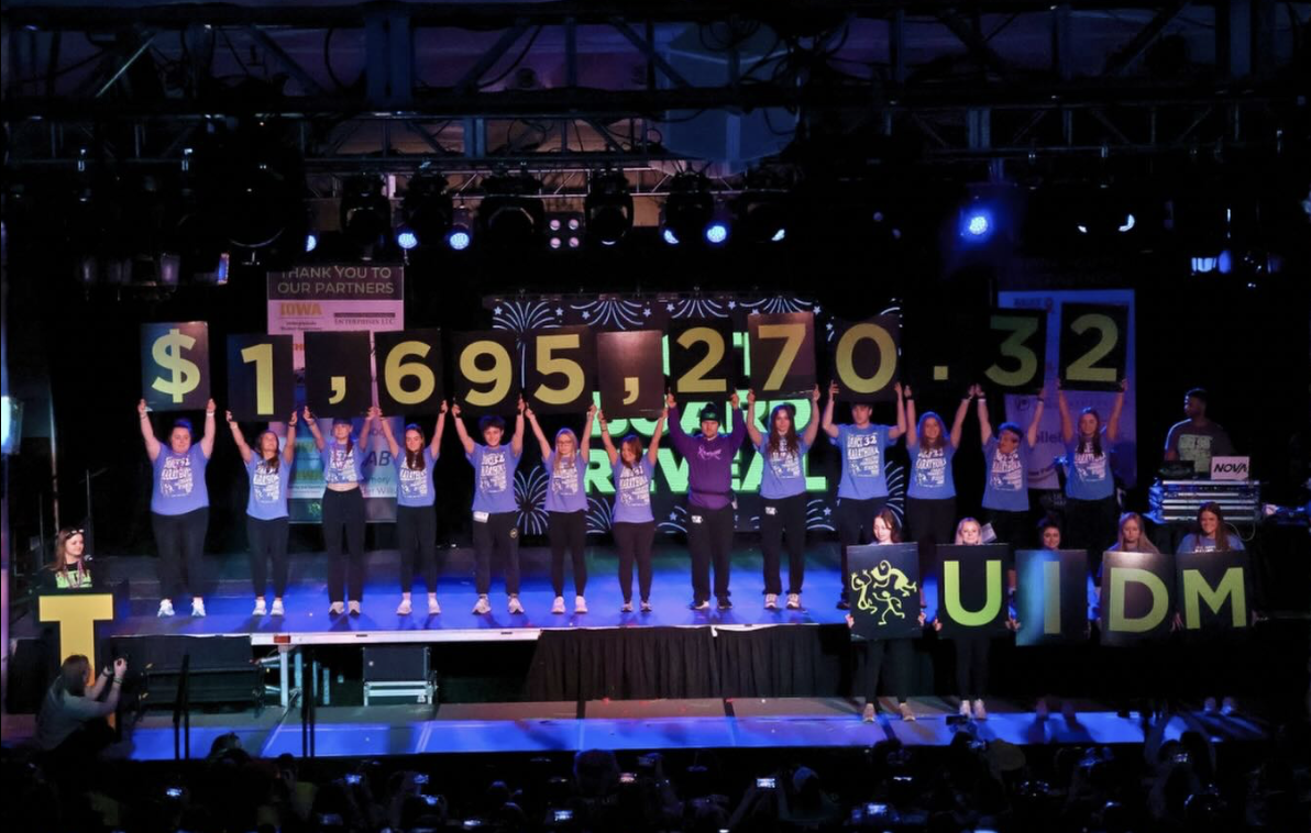 People on stage at Dance Marathon holding signs that spell out the money raised at Dance Marathon 2026: $1,695,270.32