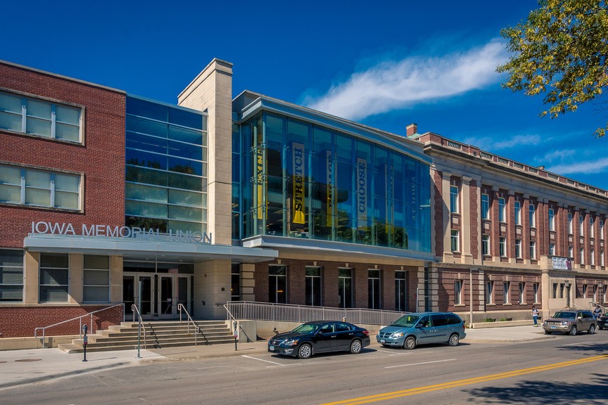 The front of the Iowa Memorial Union building. Long, black and gold Hawkeye banners hang in its tall glass windows. 