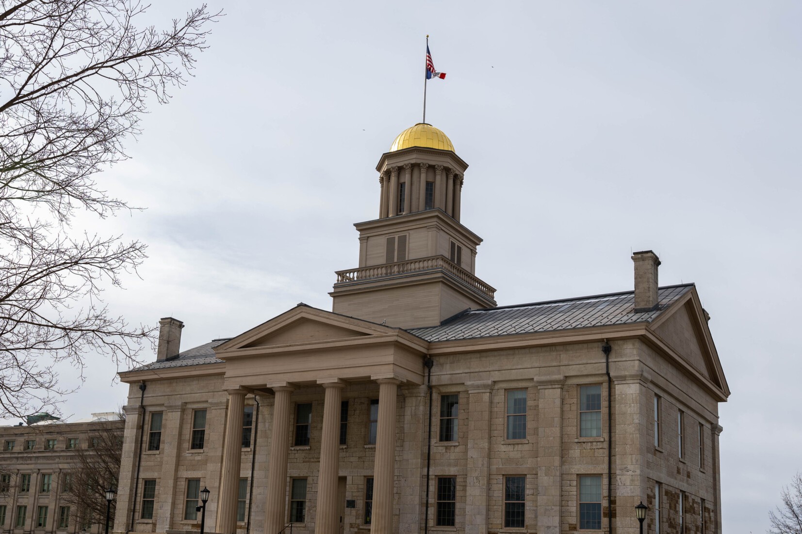 Iowa's Old Capitol Building with a flag on top. The gold dome is gleaming in the pale winter sunlight.
