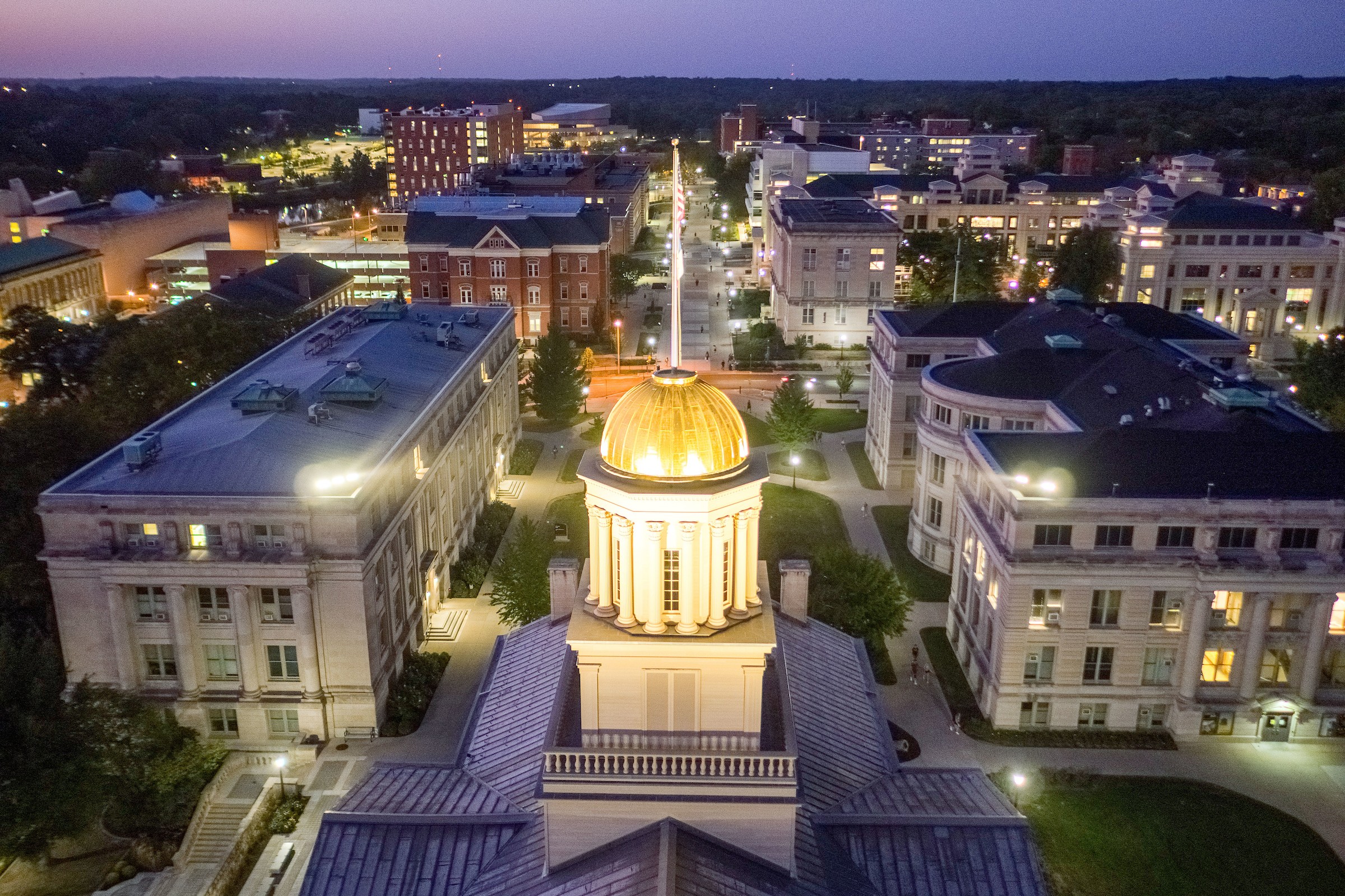 A drone view of the Old Capitol building at dusk with the gold dome bathed in lights.